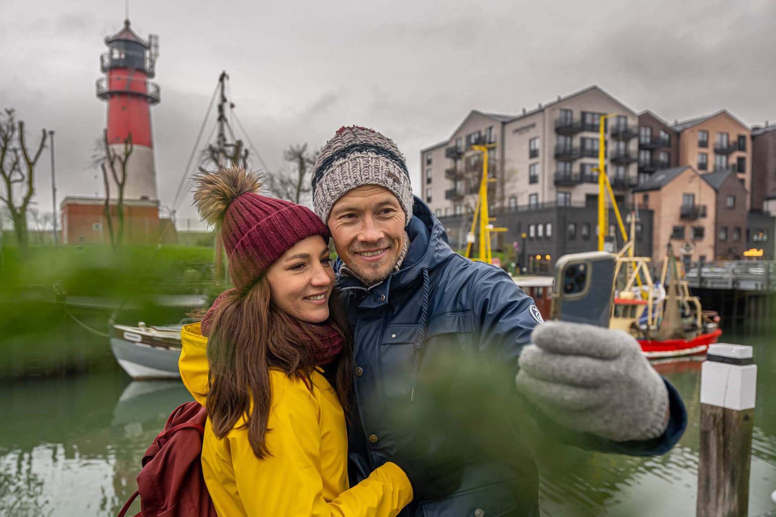 Ein Paar macht ein Selfie mit dem Leuchtturm am Museumshafen in Büsum.