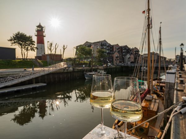Winzerfest in Büsum, Schiffe liegen im Hafen, zwei Weingläser vor dem Leuchtturm
