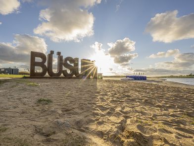 Büsum-Schriftzug in großen Buchstaben im Sand gestellt in der Familienlagune auf der Watt'n Insel.
