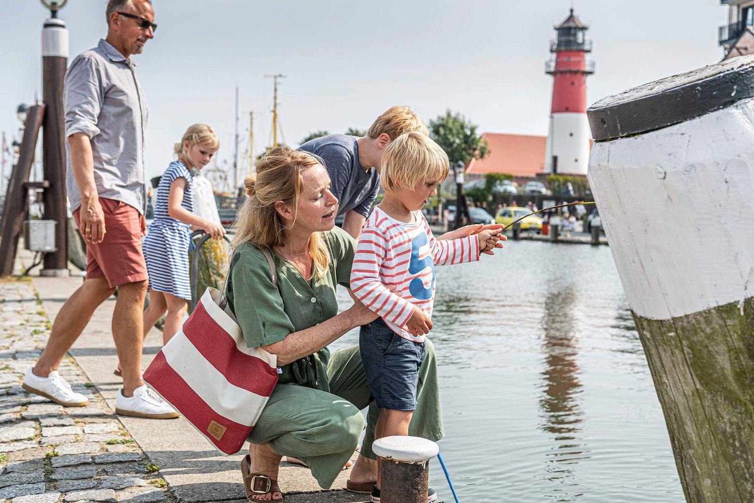 Eine Familie steht am Rand des Hafenbeckens von Büsum und schaut auf das Wasser.