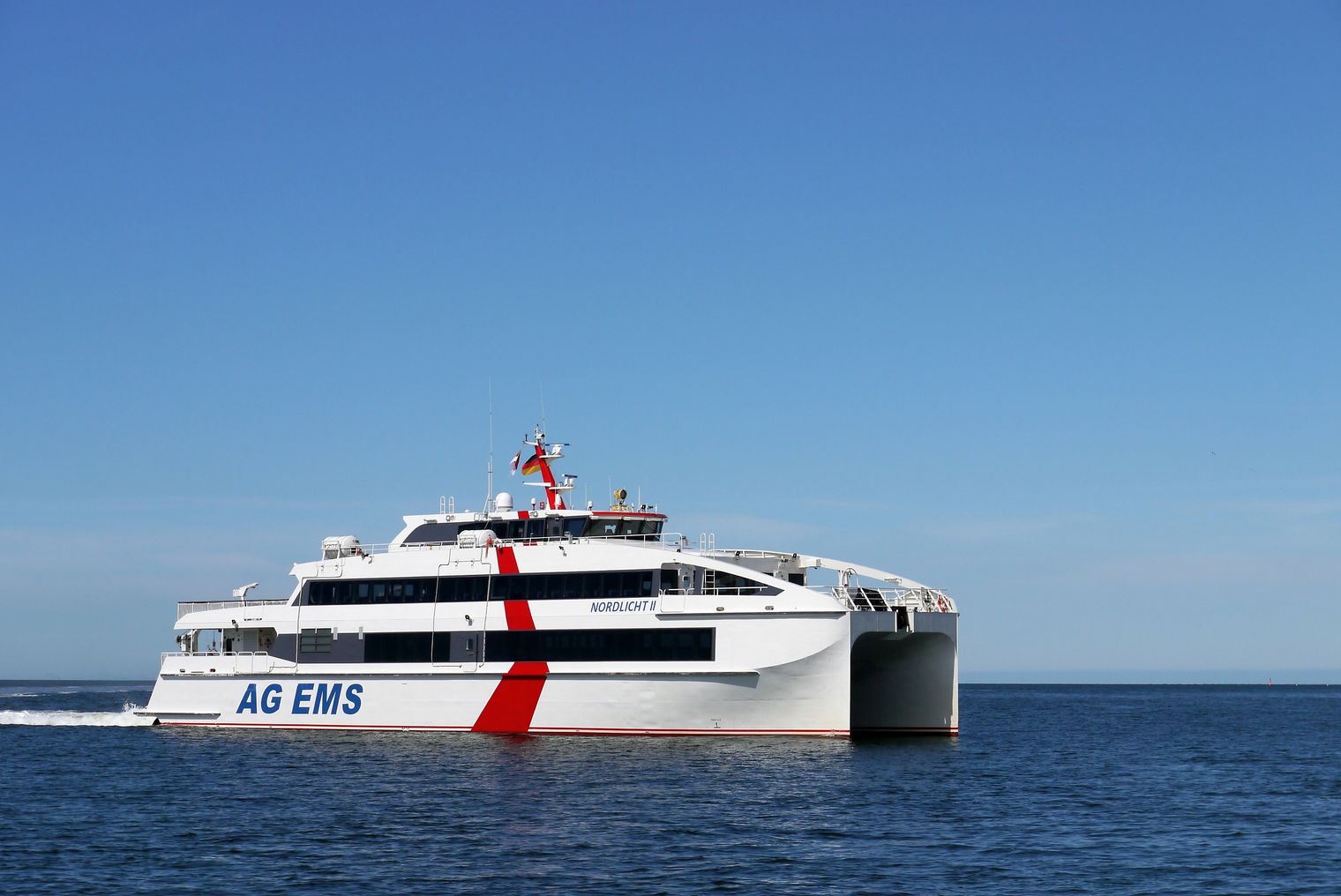 Ein weißer Katermaran auf offenem Meer und bei blauem Himmel.