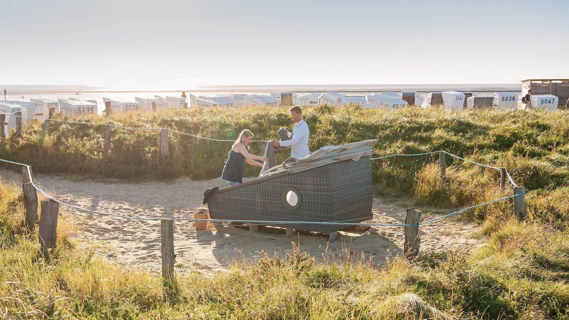 Ein Paar mit einem Schlafstrandkorb auf der Watt'n Insel in Büsum.