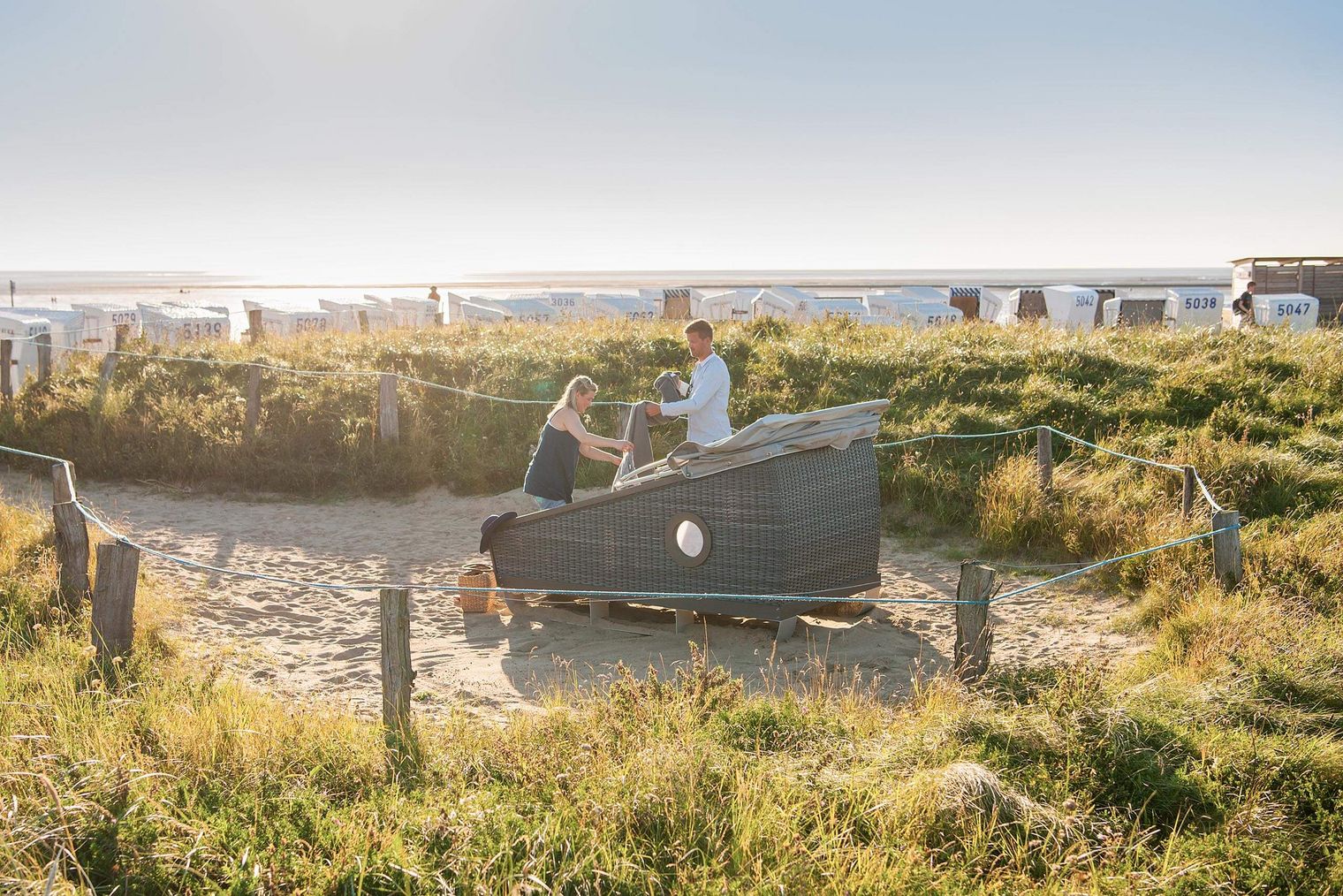 Ein Paar mit einem Schlafstrandkorb auf der Watt'n Insel in Büsum.