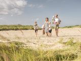 Eine Familie spaziert entspannt am Sandstrand in Büsum durch den Sand.