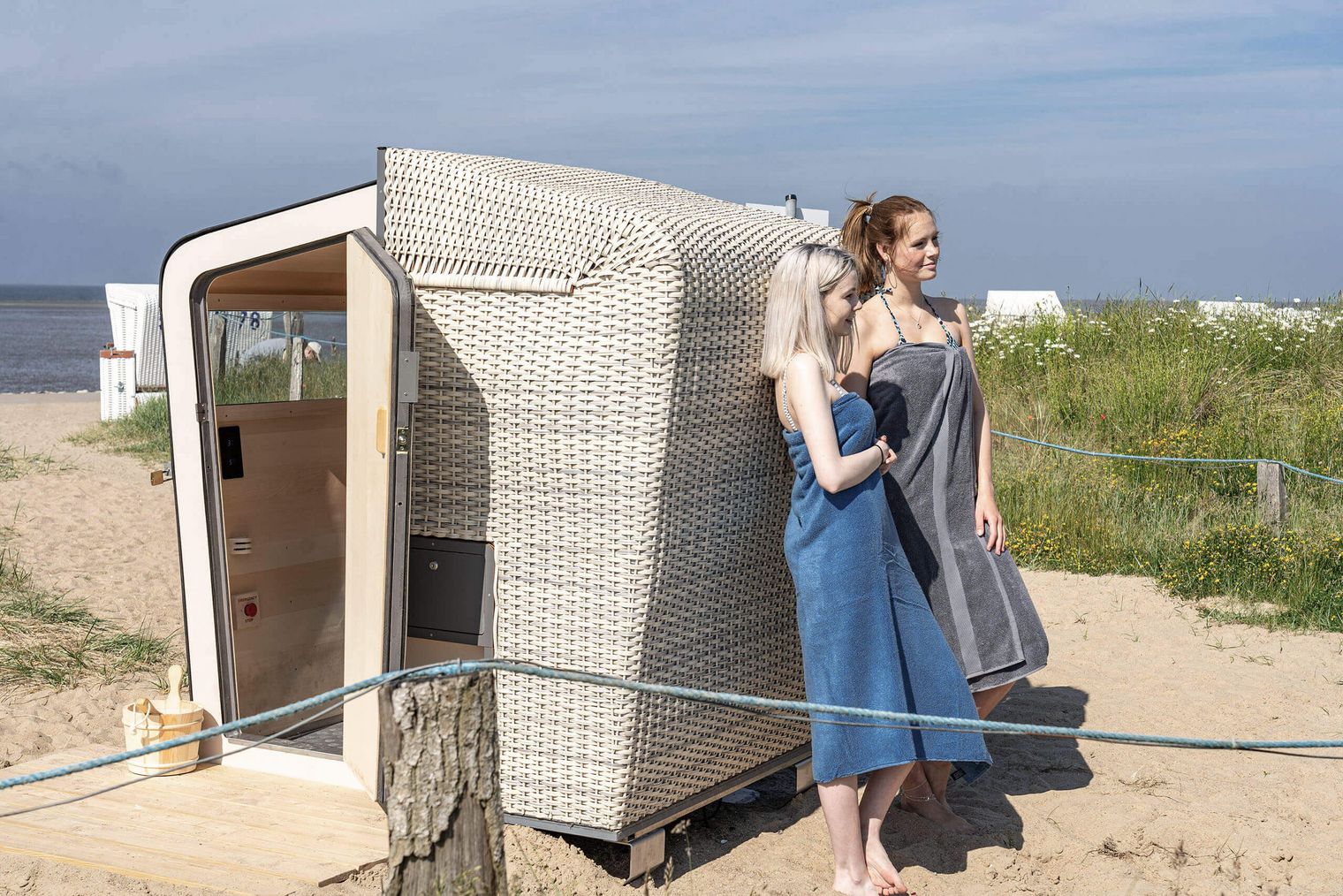 Zwei Frauen lehnen sich an die Strandkorbsauna auf der Familienlagune in Büsum.