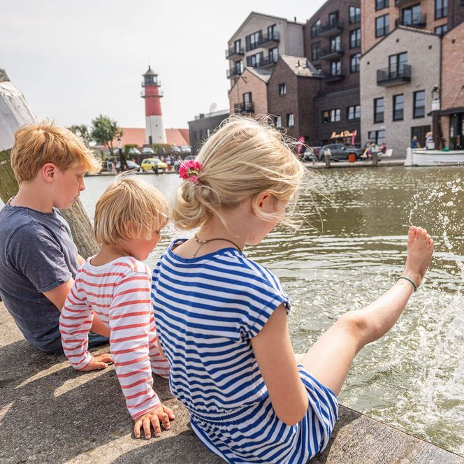Kinder strampeln mit den Beinen im Wasser des Büsumer Museumshafens.
