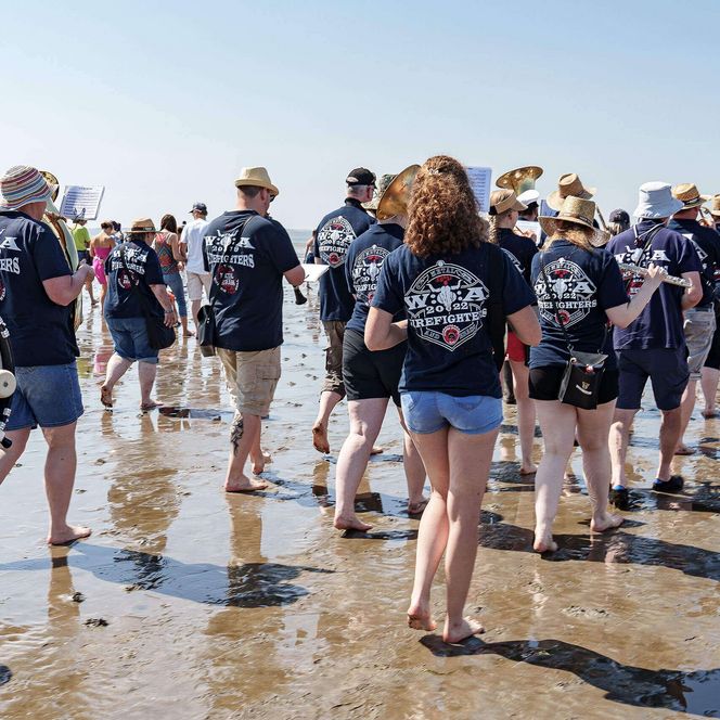 Der Musikzug Wacken Firefighters beim Wattenlaufen mit Musik in Büsum.