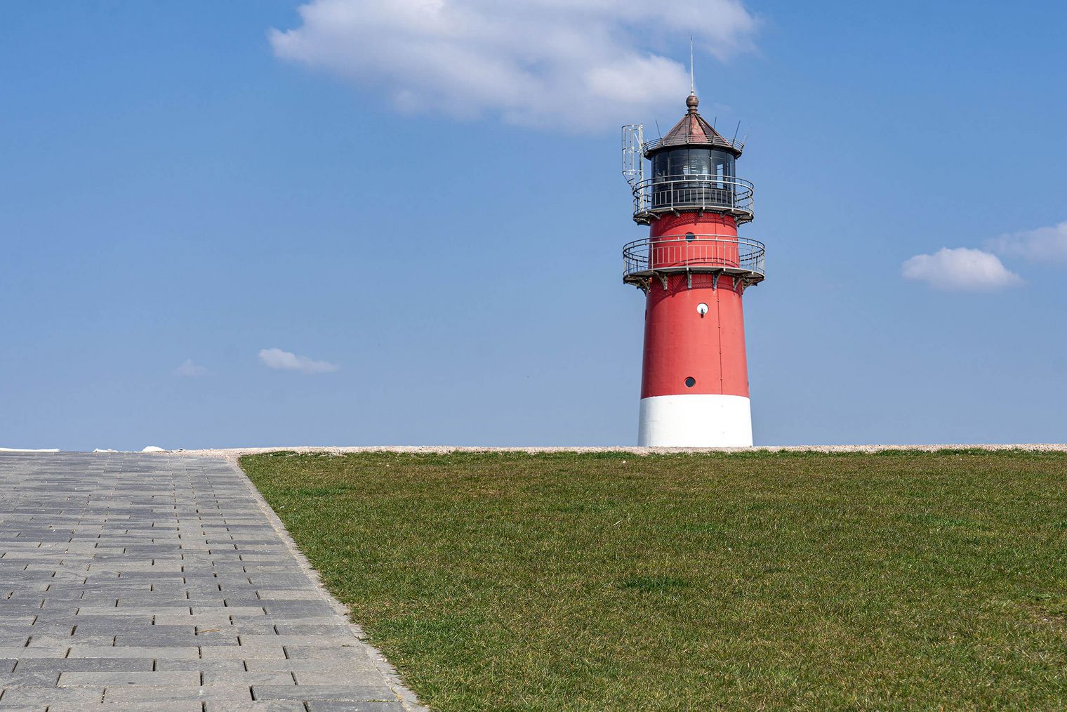 Der Leuchtturm von Büsum schaut hinter dem Deich hervor.