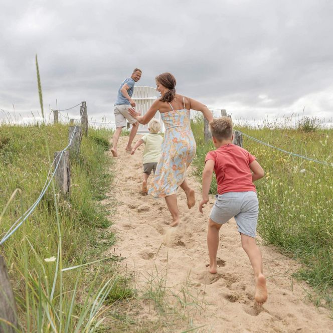 Eine Familie läuft eine Düne auf der Watt'n Insel in Büsum hoch.