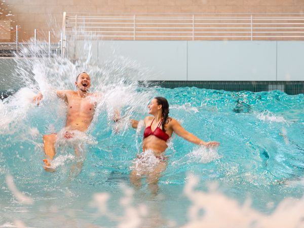 Zwei Erwachsene haben Spaß im Wellenbecken der Meerzeit Büsum.