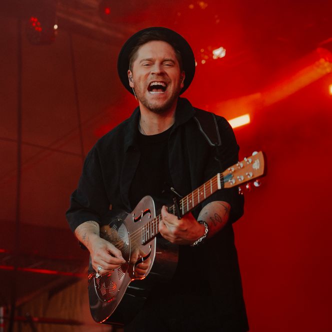 Ein Musiker in dunkler Kleidung und Gitarre auf der Bühne