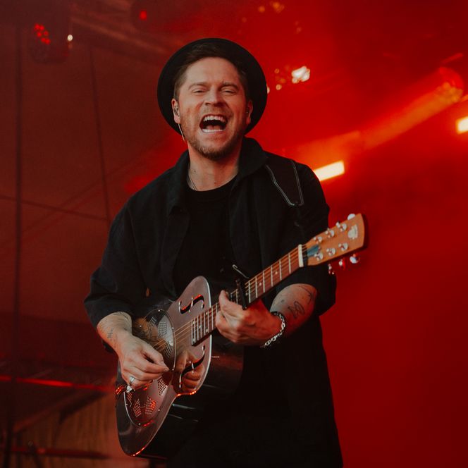 Ein Musiker in dunkler Kleidung und Gitarre auf der Bühne