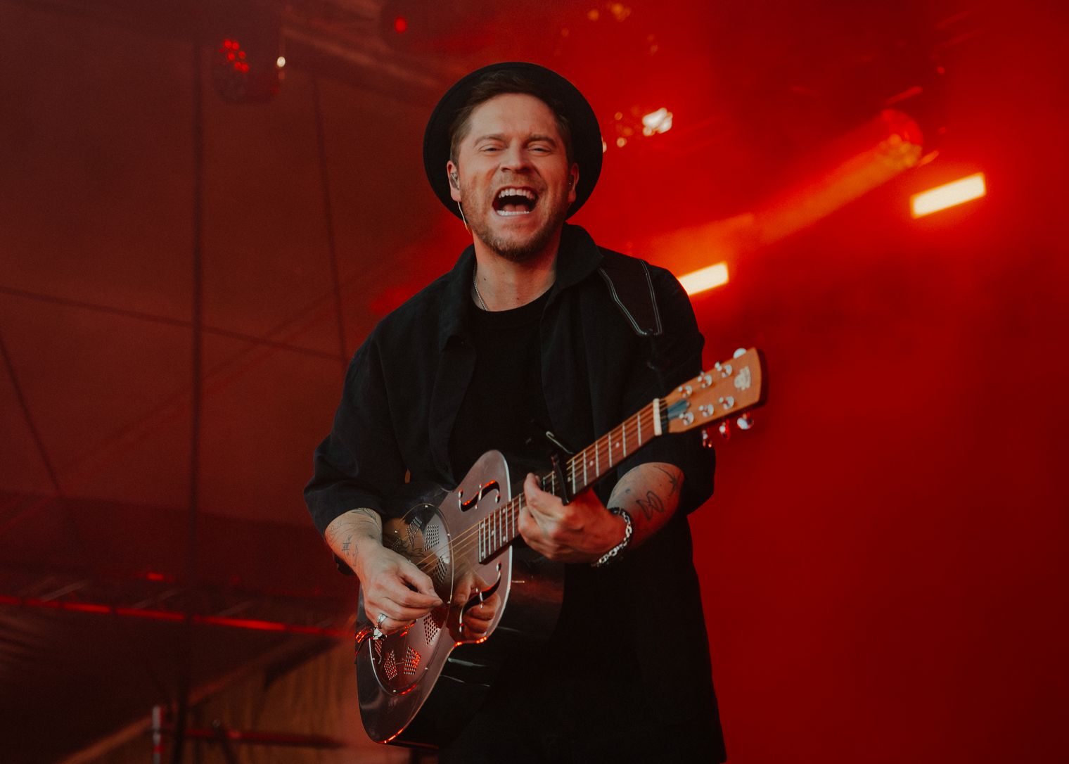 Ein Musiker in dunkler Kleidung und Gitarre auf der Bühne