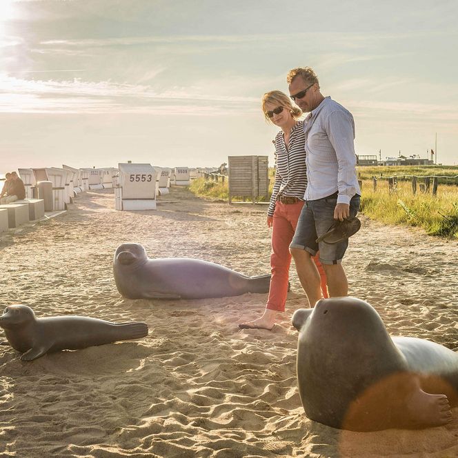 Ein Paar geht spazieren an den Bronze-Skulpturen auf der Watt'n Insel in Büsum.