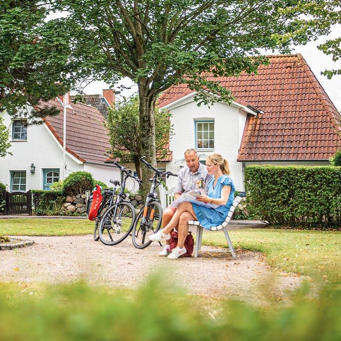 Ein Paar mit Fahrrädern auf dem Camaret sur Mer Platz in Büsum.