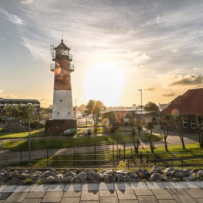 Der Büsumer Leuchtturm mit Tonnenhof bei Sonnenaufgang.