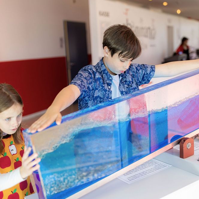 Drei Kinder untersuchen ein Ausstellungsstück im Erlebniszentrum und Mitmachmuseum Phänomania Büsum.