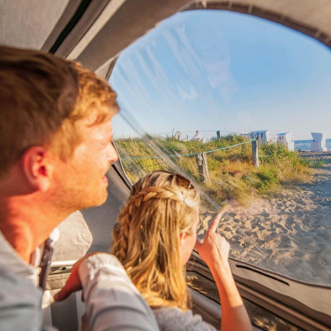 Ein Paar sitzt im Schlafstrandkorb in Büsum und guckt hinaus auf die Nordsee.