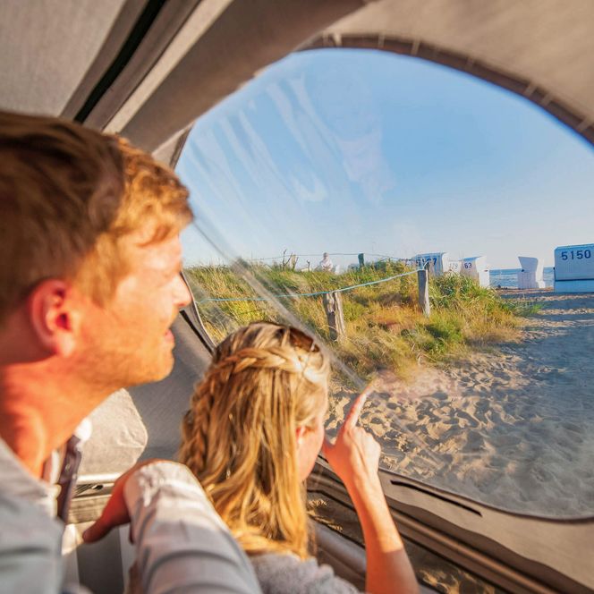 Ein Paar sitzt im Schlafstrandkorb in Büsum und guckt hinaus auf die Nordsee.