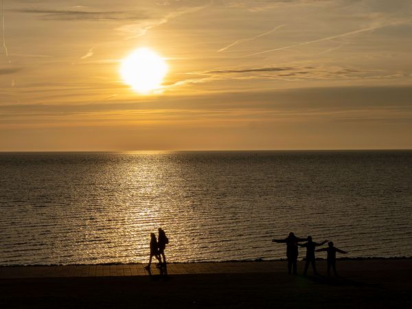 Sonnenuntergang am Büsumer Deich mit Spaziergängern