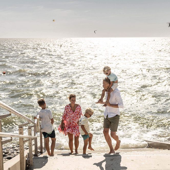 Eine Familie auf der Treppe ins Meer am Büsumer Strand.