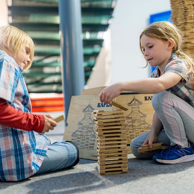 Zwei Kinder bauen einen Turm aus Holzklötzen im Erlebniszentrum und Mitmachmuseum Phänomania Büsum.
