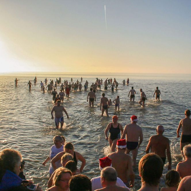 Viele Personen gehen beim Neujahrsanbaden in Badekleidung in die Nordsee vor Büsum.
