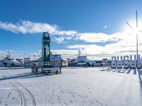 Der verschneite Büsumer Ankerplatz mit Büsum Schriftzug und Persiluhr.