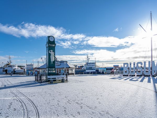 Der verschneite Büsumer Ankerplatz mit Büsum Schriftzug und Persiluhr.