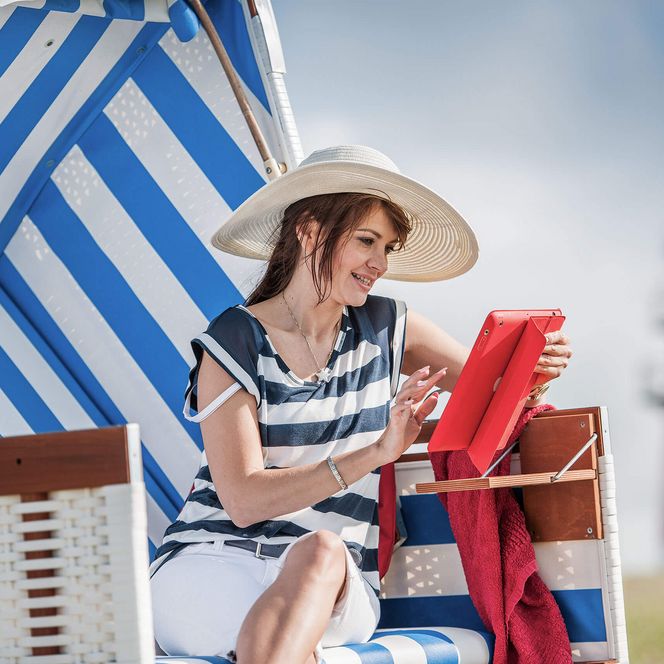 Eine Frau sitzt mit einem Tablet in der Hand in einem Büsumer Strandkorb.