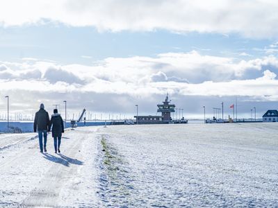 Buesum-Winter-am-Deich.jpg Spaziergänger auf dem verschneiten Deich laufen Richtung Schleuse.