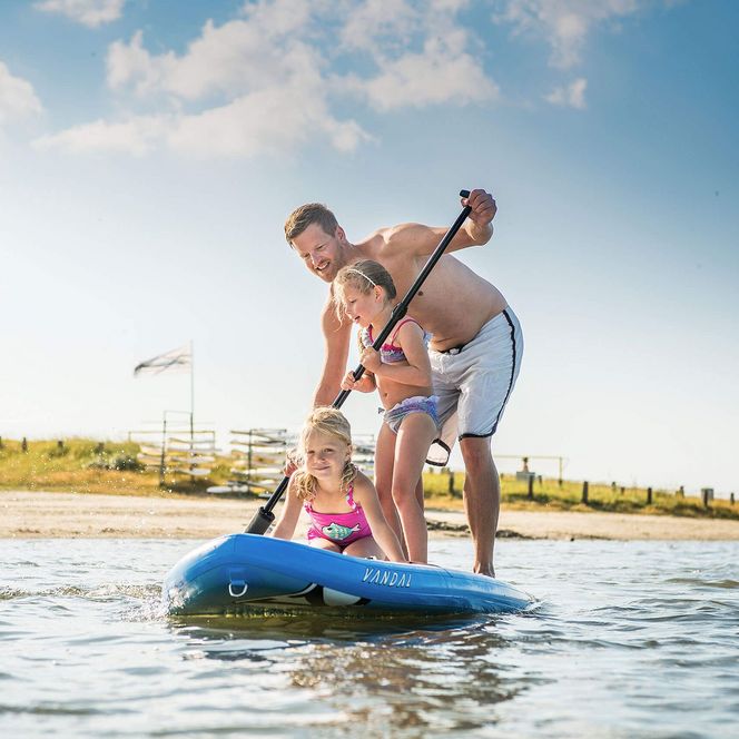 Vater mit zwei Mädchen auf einem SUP-Board in der Familienlagune in Büsum.