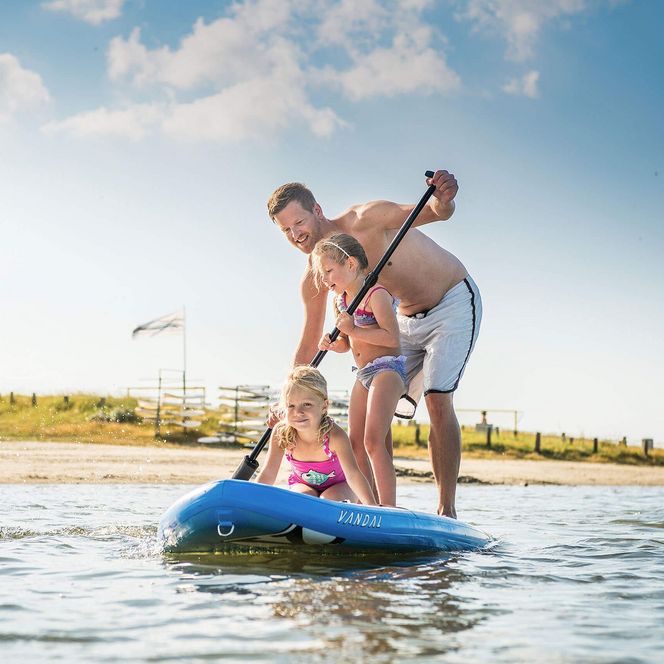 Vater mit zwei Mädchen auf einem SUP-Board in der Familienlagune in Büsum.