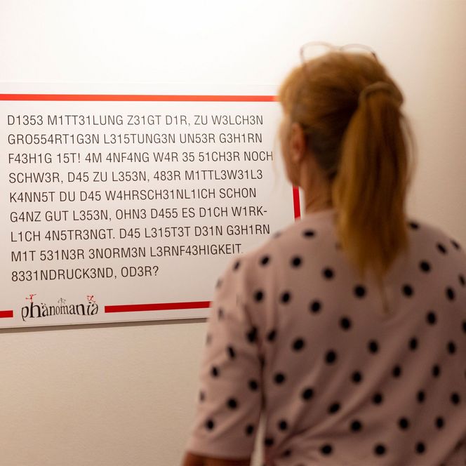 Eine Frau liest ein Schild im Erlebniszentrum und Mitmachmuseum Phänomania Büsum.