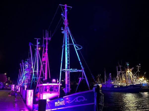 Beleuchtete Kutter liegen im Büsumer Hafen.