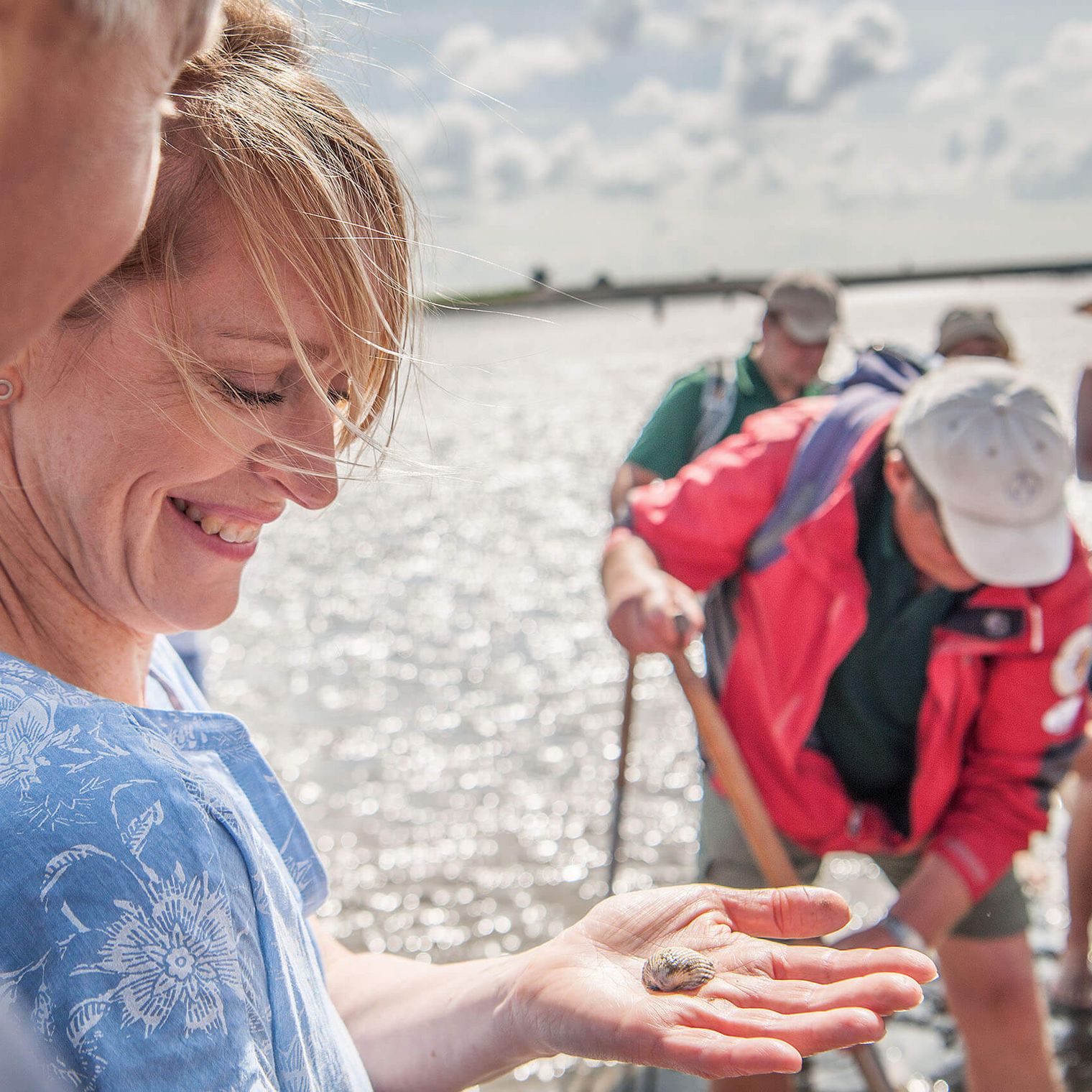 Eine Frau hält bei einer Wattführung in Büsum eine Muschel in der Hand.