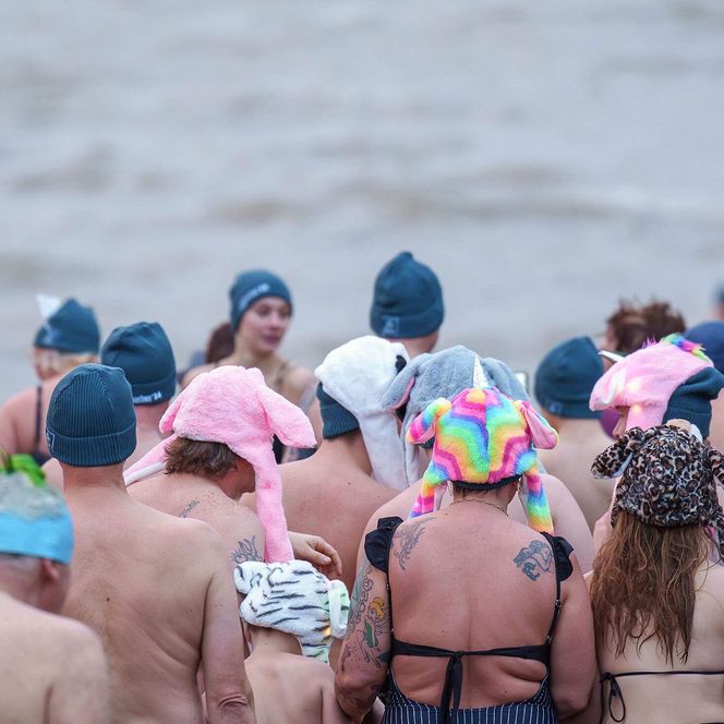 Viele Personen stehen auf der Büsumer Watt-Tribüne für das Neujahrsanbaden bereit.