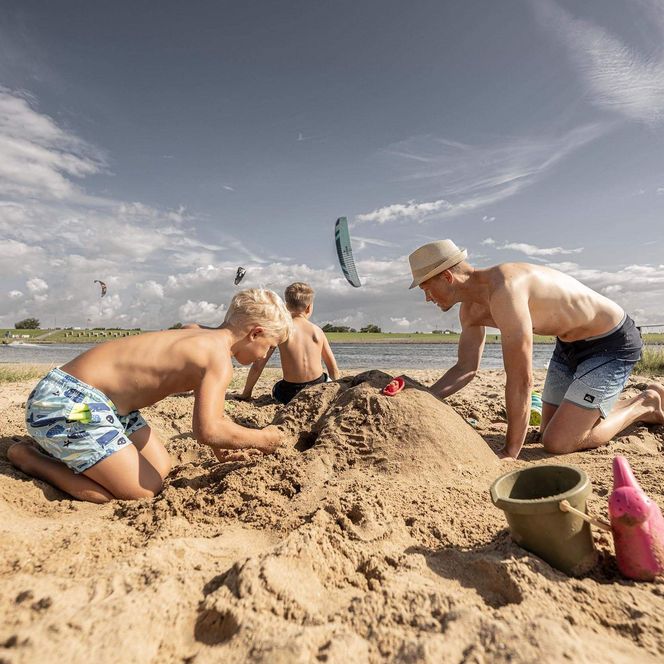 Eine Familie baut eine Sandburg am Sandstrand in Büsum.