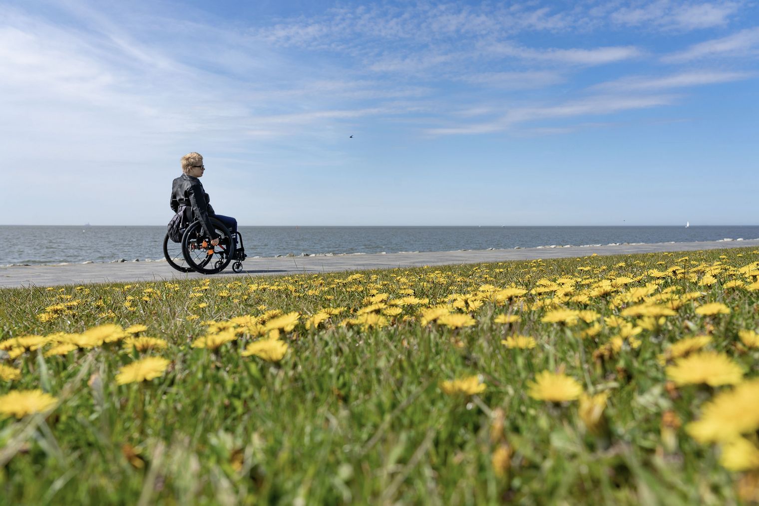 Eine Frau in Rollstuhl am Deich von Büsum.