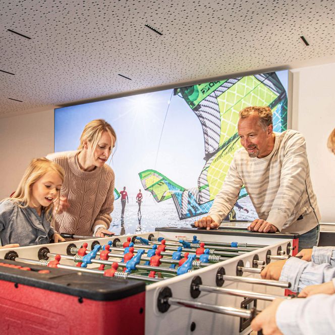 Eine Familie spielt Tisch-Kicker in der Deichbude im Büsumer Watt'n Hus.